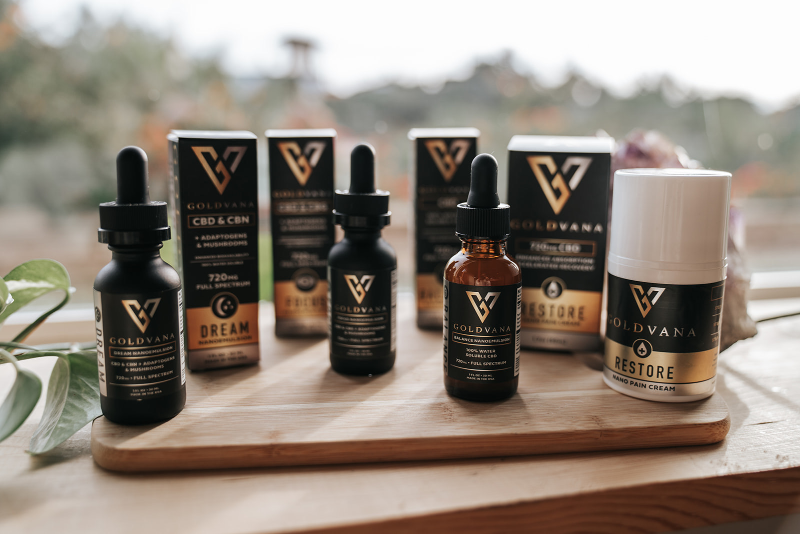 Goldvana's water-soluble functional tinctures and CBD pain cream standing on a wooden board